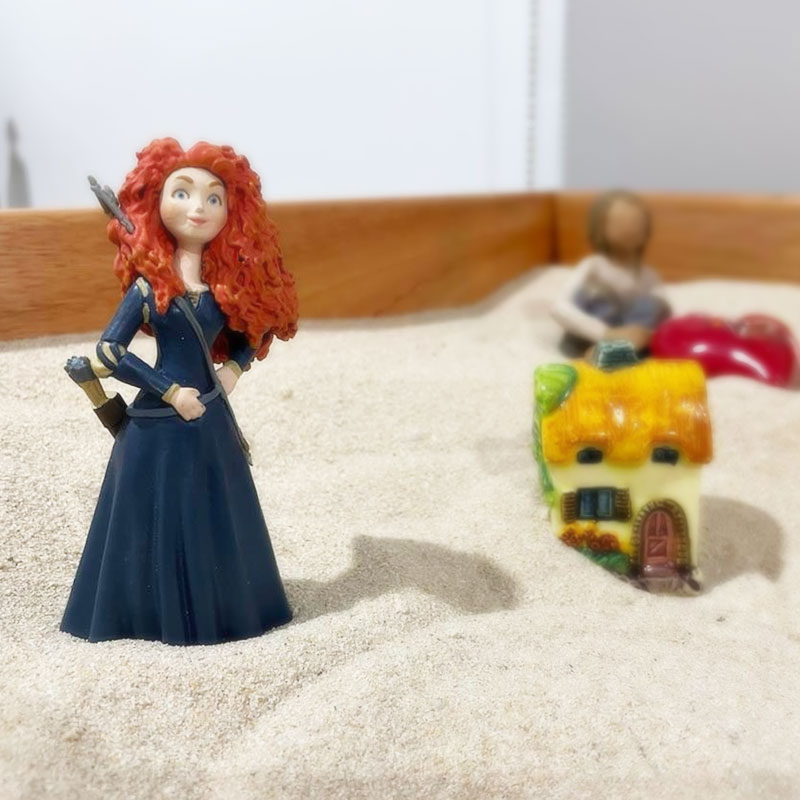 A completed sandplay therapy tray with miniature figures and symbols arranged in sand